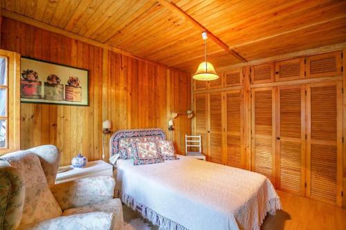 a bedroom with a bed and a couch and wooden walls at LovelyStay - Toca dos Coelhos in Marco de Canaveses