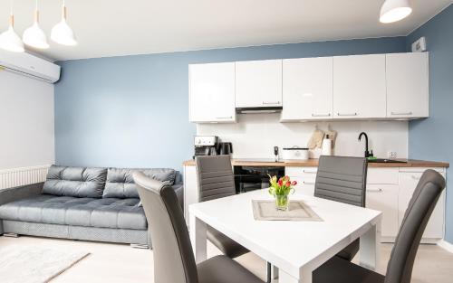 Apartament Future في كولوبرزيغ: مطبخ وغرفة معيشة مع طاولة وكراسي بيضاء