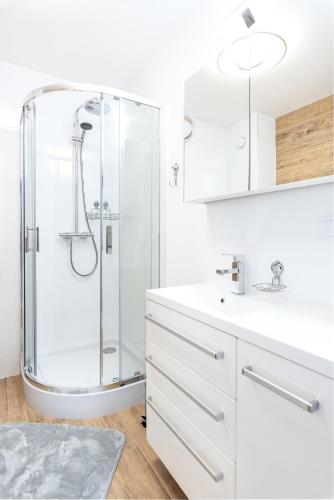 a white bathroom with a shower and a sink at Apartament Future in Kołobrzeg