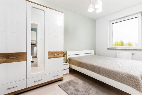 a white bedroom with a bed and a mirror at Apartament Future in Kołobrzeg