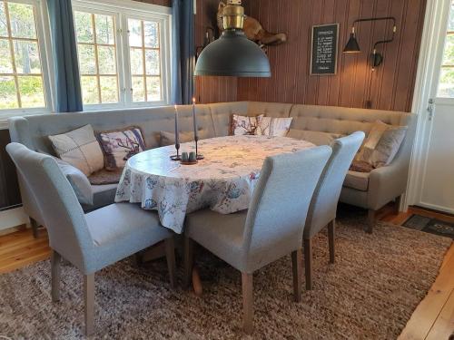 a dining room with a table and chairs and a couch at Solhytta Fantastisk beliggenhet! Hytte til leie på Skrim! in Kongsberg
