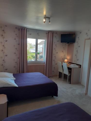 1 dormitorio con cama, escritorio y ventana en Au puits enchanté, en Saint-Martin-en-Bresse