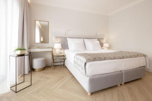 a white bedroom with a large bed and a mirror at Maritime Residence in Międzyzdroje