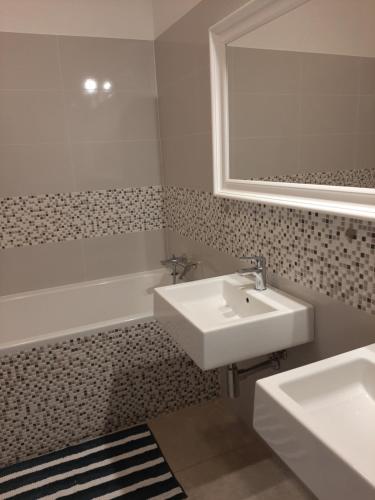 a bathroom with a sink and a tub and a mirror at Apartmán Pri Jazere - Slnečné jazerá JUH in Senec
