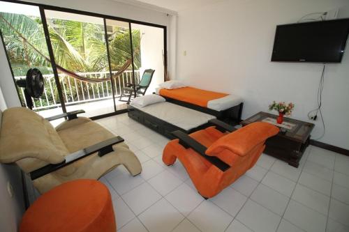Cette chambre comprend deux lits, une télévision et des chaises. dans l'établissement Patuca Apartamentos By DANP, à Santa Marta