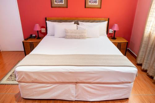 a large white bed in a room with red walls at Ngwenya Hotel & Conference Centre in Klerksdorp