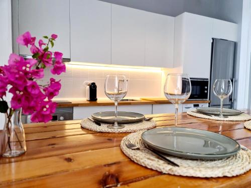 una mesa de madera con dos platos y dos copas de vino en Casa Lara by HnM, en Tavira