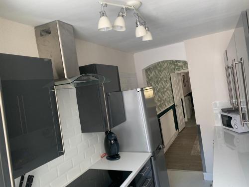 a kitchen with black and white cabinets and a refrigerator at 13 Hooton Cottage 3 Bed in Kilnhurst