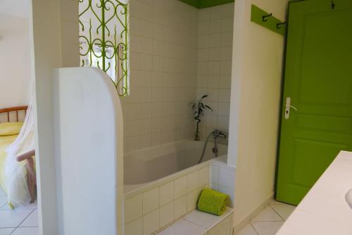 a bathroom with a tub and a green door at A L'Orée du Bois in Rétaud