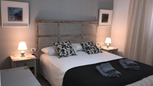 una camera da letto con un letto con cuscini e due lampade di Apartamentos Burgao a Caleta de Sebo
