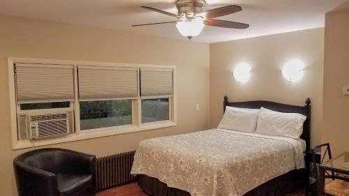 um quarto com uma cama, uma ventoinha de tecto e 2 janelas em HA Whitney Inn em Columbus
