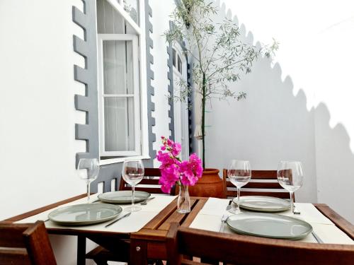 una mesa con gafas y un jarrón con flores rosas en Casa Lara by HnM en Tavira