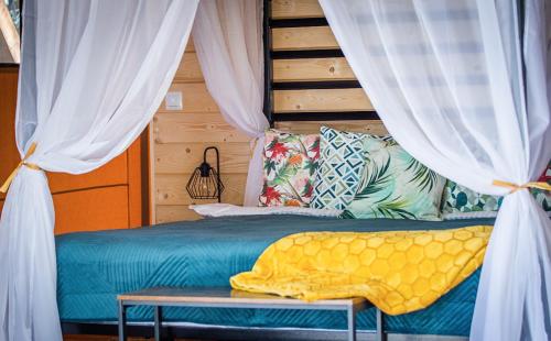 1 dormitorio con 1 cama con cortinas blancas en Kaskada Glamping en Lodz