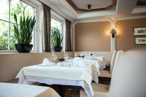 a restaurant with white tables and chairs and windows at Hotel Rablanderhof in Rablà