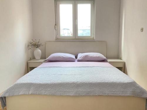 a bedroom with a bed with two pillows and a window at Apartman Krešo in Makarska