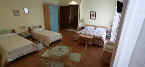 a room with two beds and a table and chairs at B&B Casa Piras IUN3880 in Barùmini
