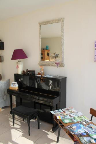 a piano in a living room with a mirror at A L'Orée du Bois in Rétaud