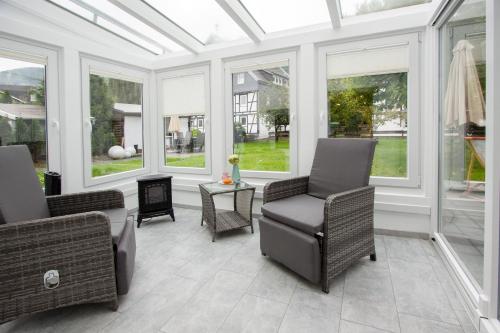 a conservatory with chairs and a table and windows at Landhotel Voss im TalVital in Saalhausen