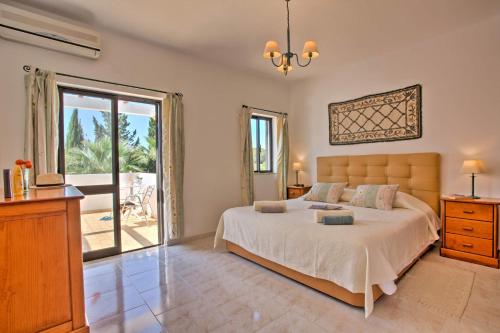 a bedroom with a large bed and a large window at Villa Candida by Villa Plus in Vale do Lobo