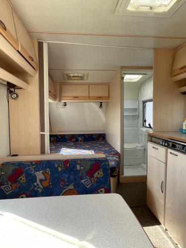 a small caravan with a bed and a kitchen at Przyczepy Kemping Polaris Półwysep Helski in Chałupy