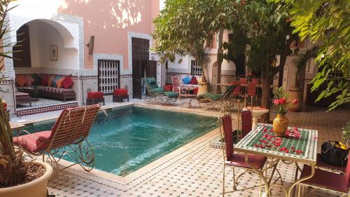a pool in a courtyard with chairs and a table at Riad Barroko in Marrakech