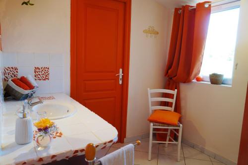 a bathroom with a sink and a red door at A L'Orée du Bois in Rétaud
