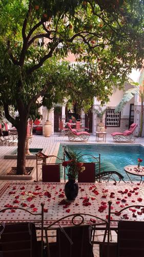 a table with flowers on it next to a swimming pool at Riad Barroko in Marrakech