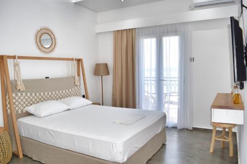 Anagennisi Hotel في سكالا: غرفة نوم بسرير ابيض كبير ونافذة