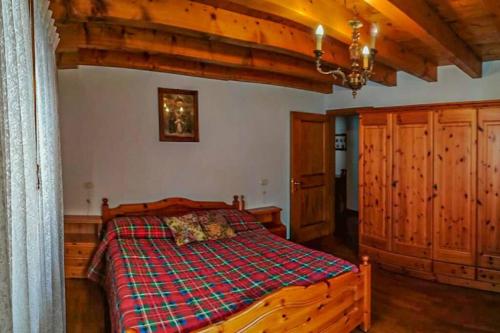 una camera con letto in legno e coperta a quadri. di Casa Francesca - Relax nel cuore delle Dolomiti a Pieve di Cadore