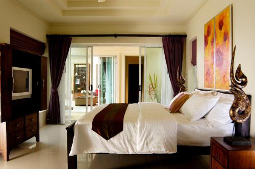a bedroom with a large bed and a television at Karon Beach Walk Villa in Karon Beach