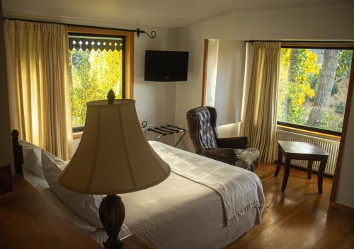 a bedroom with a bed and a chair and a window at El Reloj Hotel in Coihaique