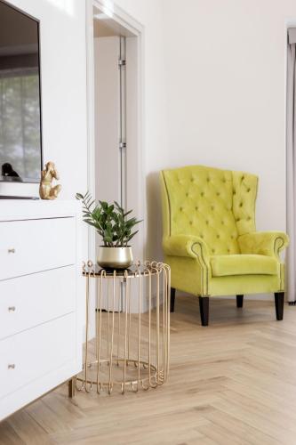 a yellow chair in a living room with a plant at Maritime Residence in Międzyzdroje