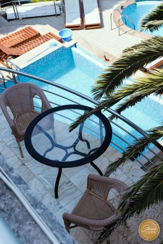 a glass table and chairs next to a swimming pool at Resort Stikovic in Dobra Voda