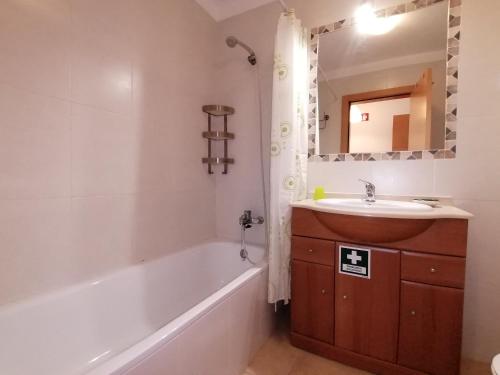 uma casa de banho com uma banheira, um lavatório e um espelho. em Encosta da Marina Beach Apartment em Portimão