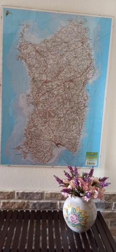 a vase with flowers sitting on a bench in front of a map at B&B Casa Piras IUN3880 in Barùmini