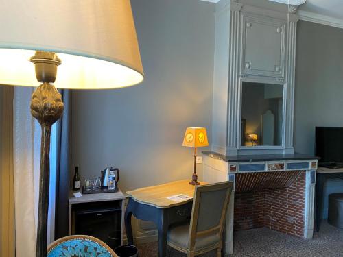 a room with a desk with a lamp and a table with a chair at Best Western Plus d'Europe et d'Angleterre in Mâcon