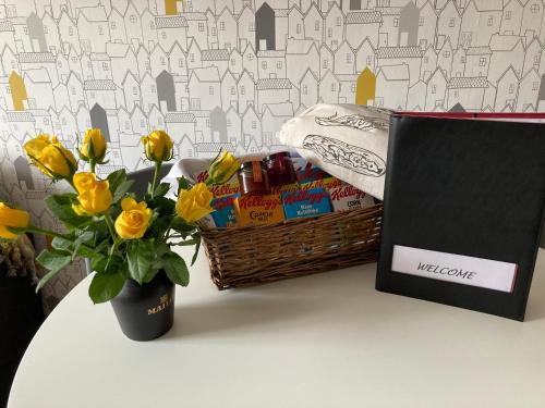 een tafel met een mand, een laptop en bloemen bij Assembly View - two bedroomed apartment with parking permit in Ludlow Town Centre in Ludlow