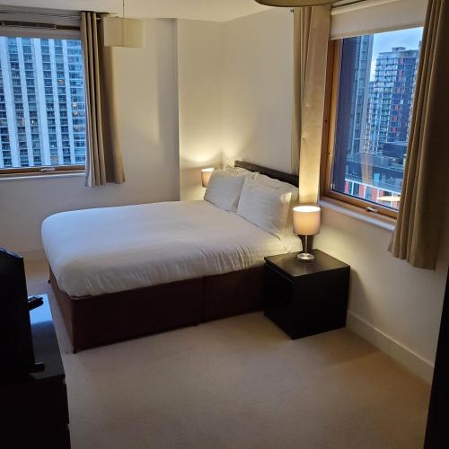 a hotel room with a bed and two windows at Captivating 2-Bed Apartment in Canary Wharf london in London