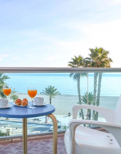 a table with two glasses and a view of the beach at KAKTUS Hotel Kaktus Albir in Albir