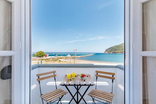 a balcony with a table with two chairs and a view of the beach at Uncle John's Guesthouse in Skopelos Town