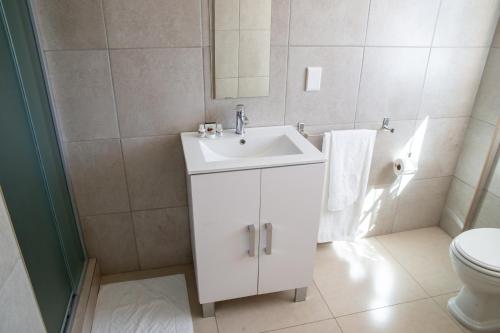 a white bathroom with a sink and a toilet at Ngwenya Hotel & Conference Centre in Klerksdorp