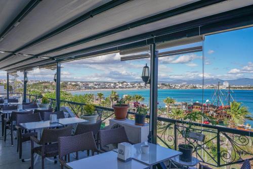 a restaurant with tables and chairs and a view of the ocean at Arden Hotel in Didim