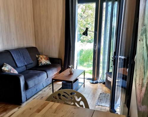 a living room with a couch and a table at Manège de la Chapinière - DadaLoge tiny-house in Châteauvieux