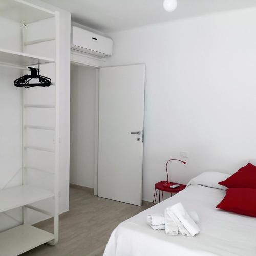 ein weißes Schlafzimmer mit einem weißen Bett und einem roten Kissen in der Unterkunft Grazioso Bilocale al mare in Marcelli