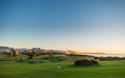 a golf course with the ocean in the background at Best Western City Sands in Wollongong