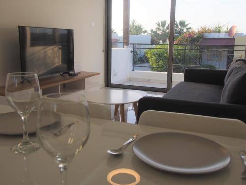 a table with two wine glasses and a living room at 42 Beach Coast Apartment in Polis Chrysochous