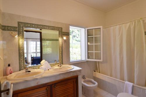 Un baño con dos lavabos, un inodoro y un espejo. en Villa Ligia by ALgest, en Portimão