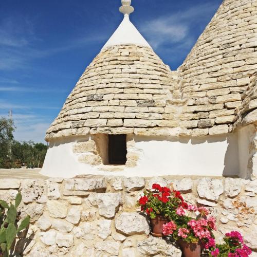 a stone building with flowers in a window at Trulli Di Spinaruta in Grottaglie