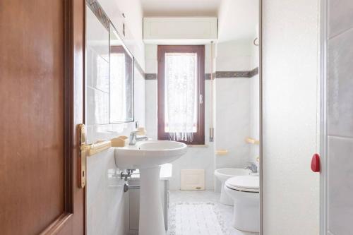bagno bianco con lavandino e servizi igienici di Casa Vacanze da Placida a Suni