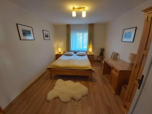 a bedroom with a bed and a desk and a window at Chata Olimpijki in Karpacz